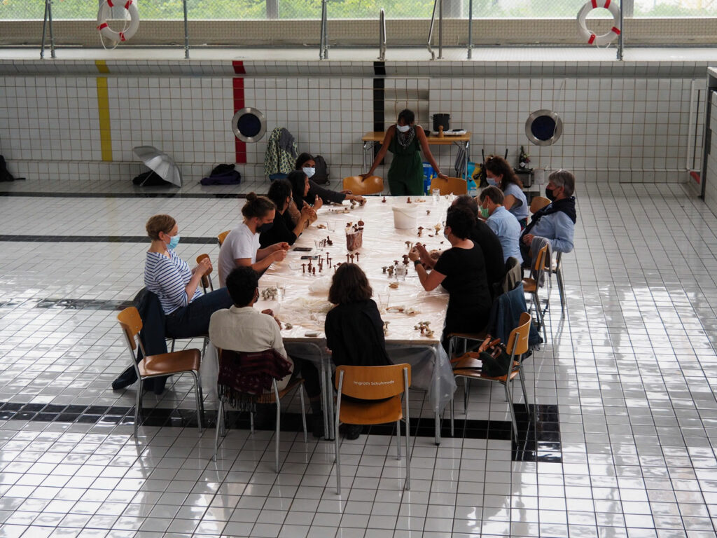 Ein grosser Tisch im NeubadPool mit 10-12 Menschen die Keramikpilze kneten